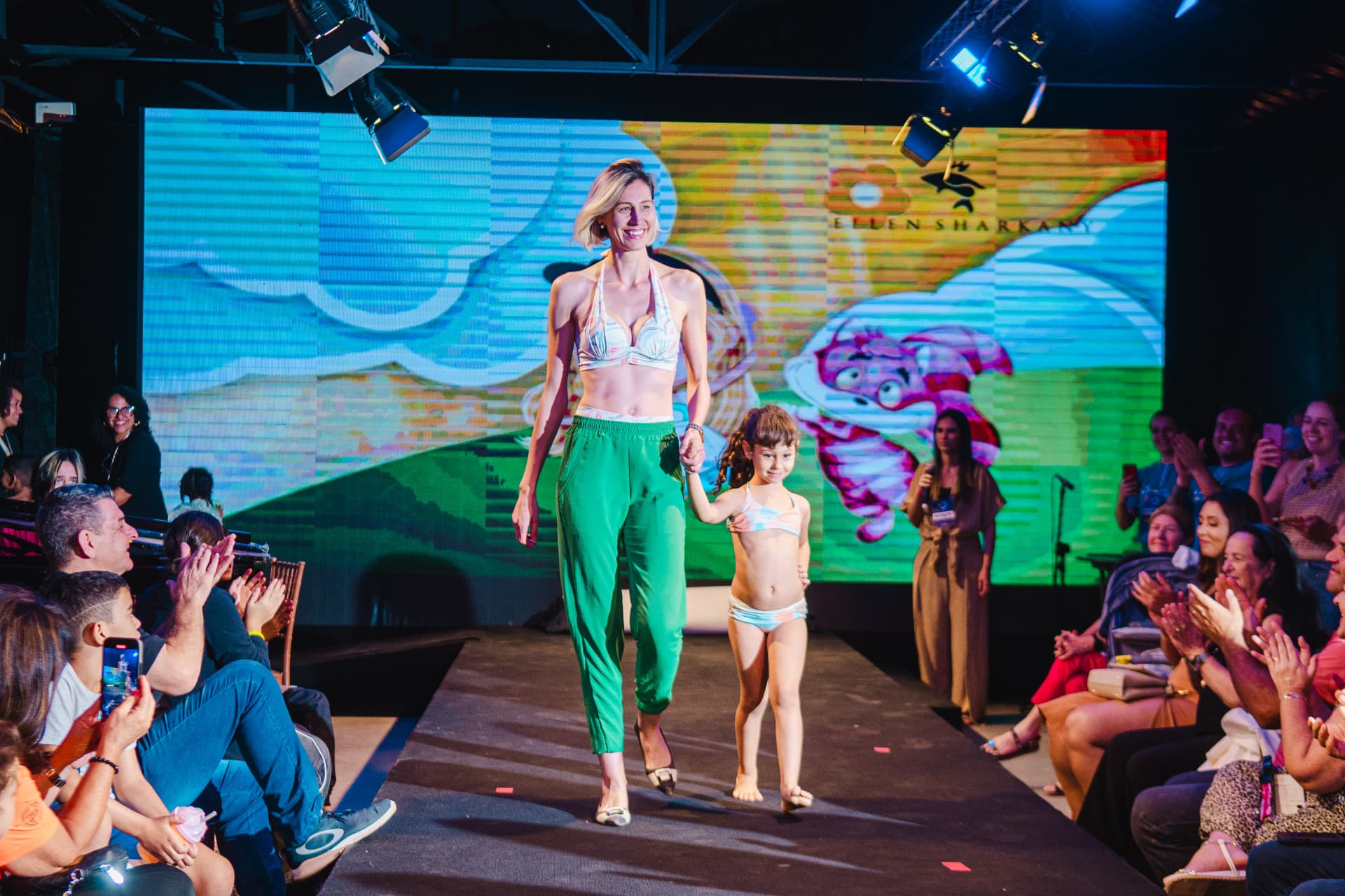 Mãe e filha desfilando de mãos dadas na passarela