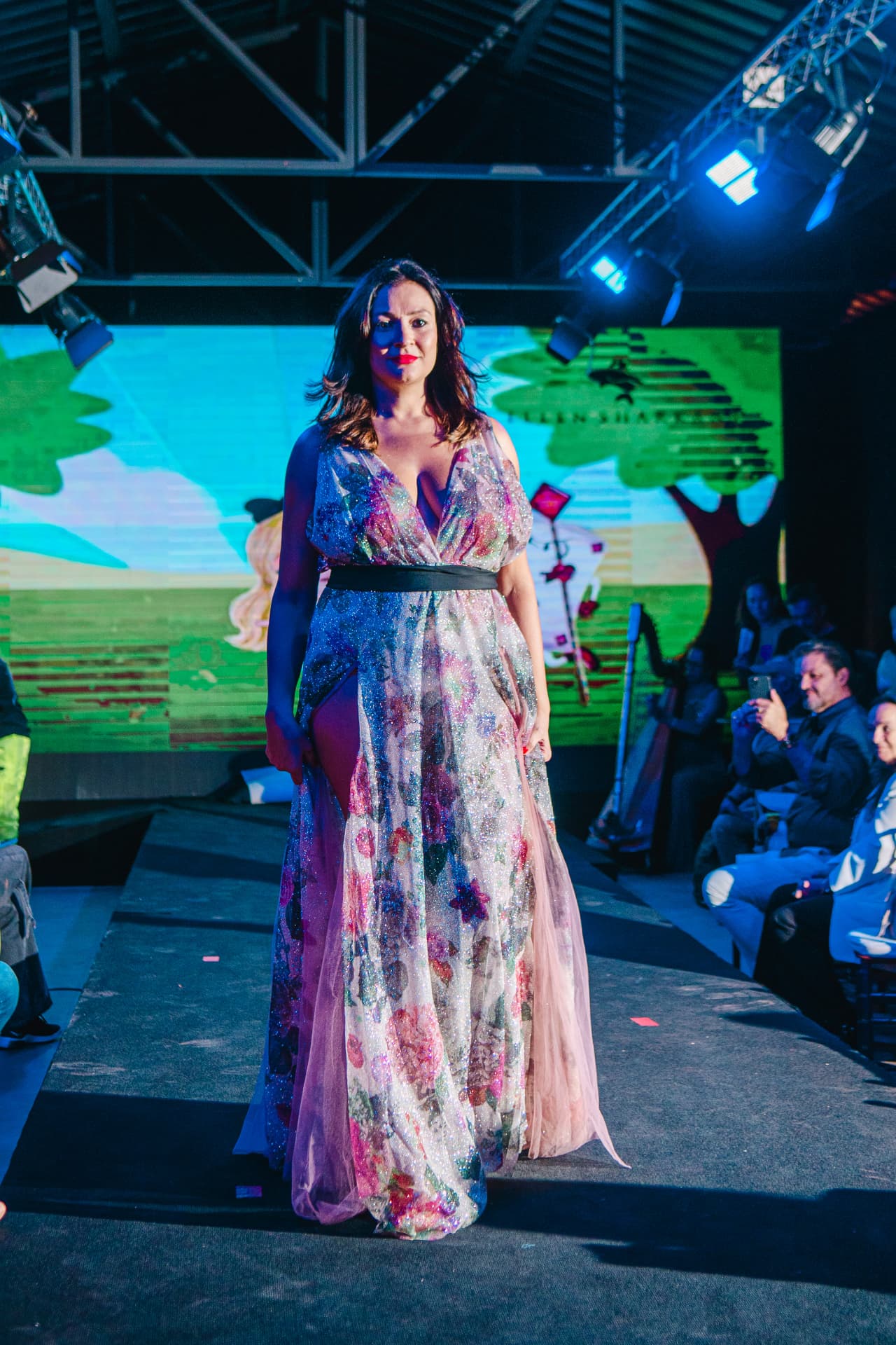 Modelo desfilando vestido longo estampado sob as luzes do palco