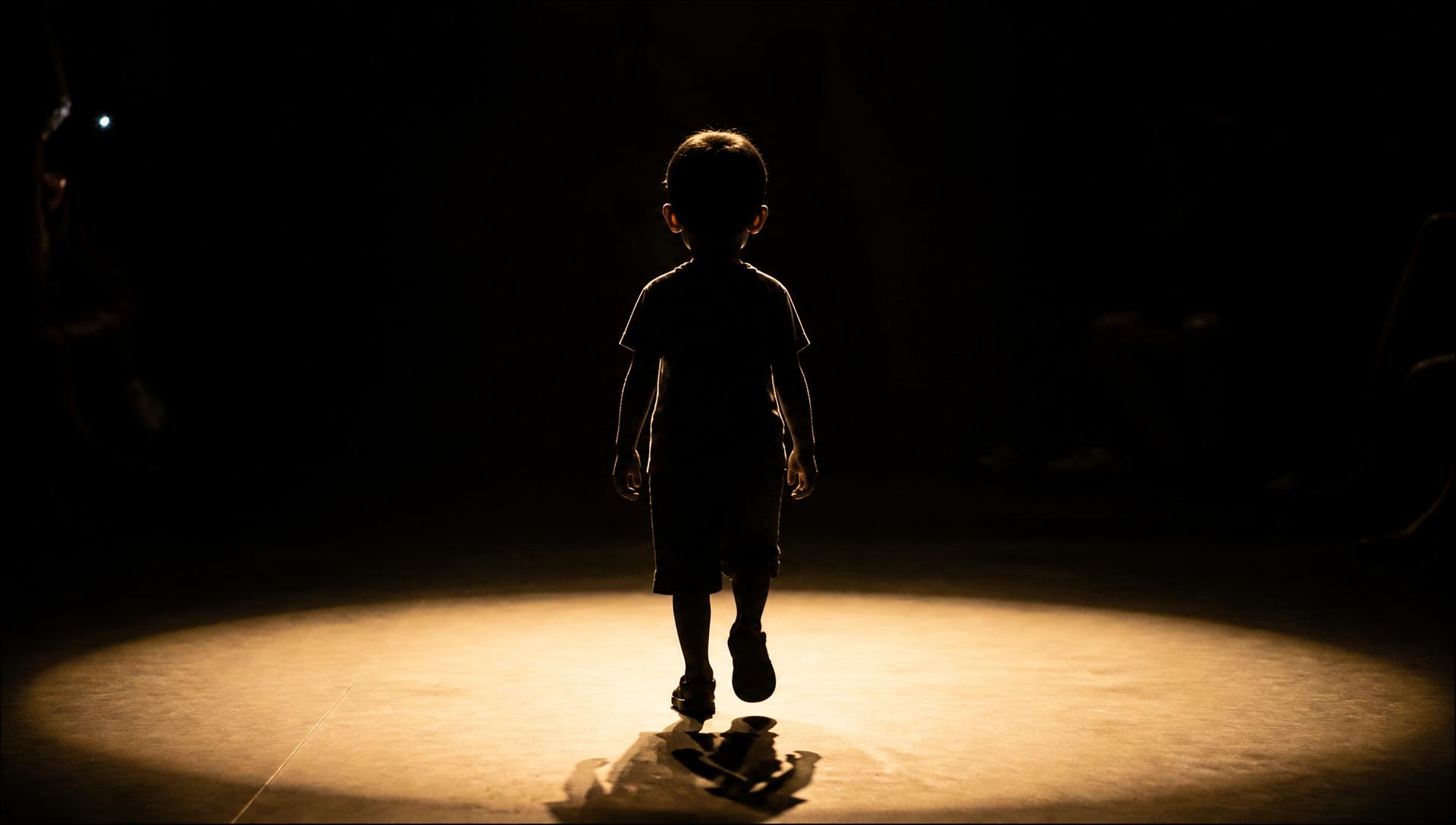 Criança caminhando sob a luz da passarela
